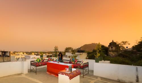 a balcony with a table and chairs on a roof at Braj Villa in Udaipur
