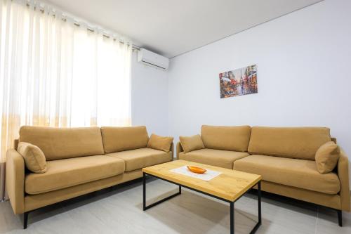 a living room with two brown couches and a coffee table at SanPietro Vacation Apartments in Durrës