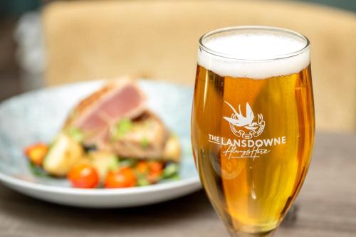 a glass of beer next to a plate of food at The Lansdowne, Eastbourne in Eastbourne