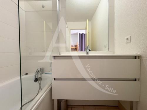 une salle de bain avec un lavabo, une baignoire et un miroir dans l'établissement STUDIO 4 PERS, PKG, PISCINE, TENNIS, VUE MER, à Sète