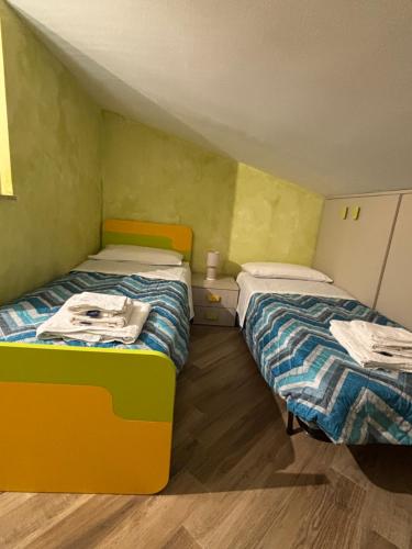 two beds in a small room with green walls at Casa Andrea Cefalù in Cefalù