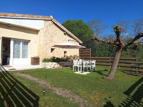 a table and an umbrella in the yard of a house at Gîte du Tourney in Faleyras