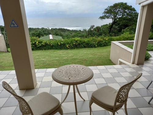 a patio with a table and chairs on a porch at Ocean Grove Guesthouse in Port Edward