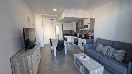 un soggiorno con un divano blu e una cucina di Edificio Calpe Beach Arenal a Calpe