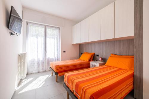 two beds in a room with orange sheets at Casa Blue Moon in Baveno