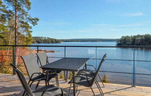 奥尔延Beautiful Home In Årjäng With Lake View的甲板上的一张桌子和几把椅子，可以欣赏到湖景