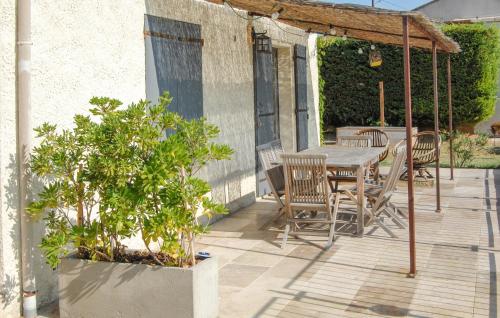 a patio with a wooden table and chairs and a table and a tree at Amazing Home In Saint Pons La Calm in Saint-Pons-la-Calm