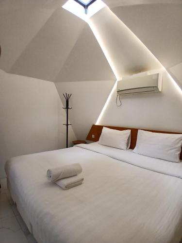 a bedroom with two beds with white sheets and a light at Grace Hill Villa Lubuk Minturun in Padang