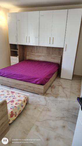a bedroom with a bed with white cabinets and purple sheets at Il Risveglio delle Onde 2 in Torre Ovo