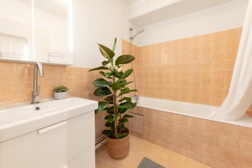 La salle de bains est pourvue d'un lavabo, d'une baignoire et d'une plante. dans l'établissement T2 cosy à 2 pas de la Garonne - Parking privé, à Toulouse