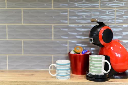 a tea kettle is sitting next to cups on a counter at Located in the peaceful NG8 Wollaton , Perfect for Business Trips & Family Holidays or working proffesionals-long term deals, M1 Nearby , Free Parking , Private Garden , 500Mb Wi-Fi , Netflix in Nottingham