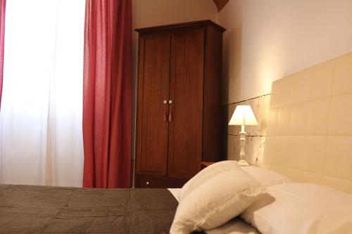 a bedroom with a bed with white pillows and a red curtain at Bed & Tower in Pisa