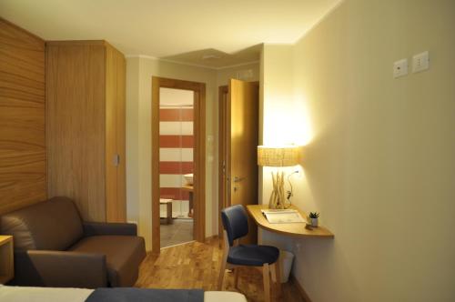 a hotel room with a bed and a desk and a couch at Hotel Miramonti in Castel del Monte