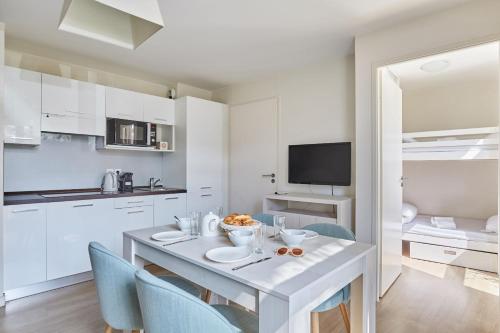 a white kitchen with a table and chairs at Résidence Odalys Les Dunes du Soleil in La Grande-Motte