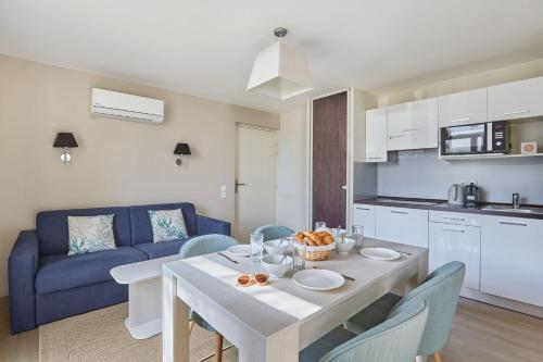 a kitchen and living room with a table and a blue couch at Résidence Odalys Les Dunes du Soleil in La Grande-Motte