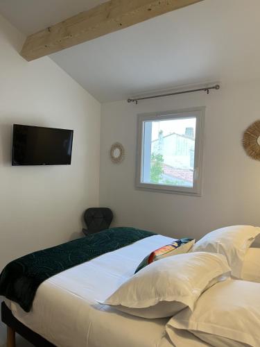 a bedroom with a bed and a tv on the wall at L Abri-côtier Appartements in Saintes-Maries-de-la-Mer
