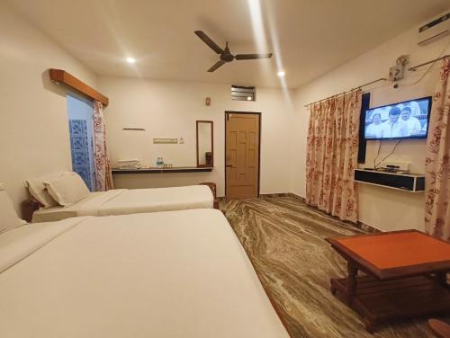 a hotel room with a bed and a flat screen tv at Hare Rama Hare Krishna - EESHA Hotel in Rāmeswaram