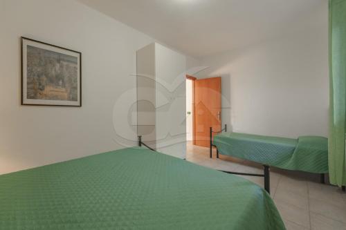 a bedroom with a green bed and a door at La Palazzina nel Verde - Goelba in Campo nell'Elba