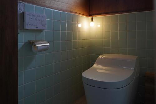 a bathroom with a toilet and a light on the wall at suo 椿の島の宿 in Oshima