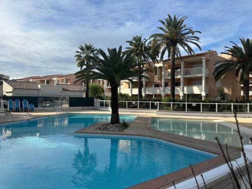 une grande piscine avec des palmiers en face d'un bâtiment dans l'établissement Appartement cosy avec terrasse, à Vallauris