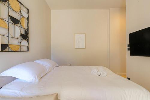 a white bed with two pillows and a television at Studio avec terrasse aux portes de Lyon, Ecully in Écully