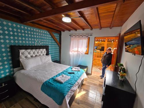 a woman standing in a bedroom with a bed at Hostal la Divisa Salento in Arrayanal