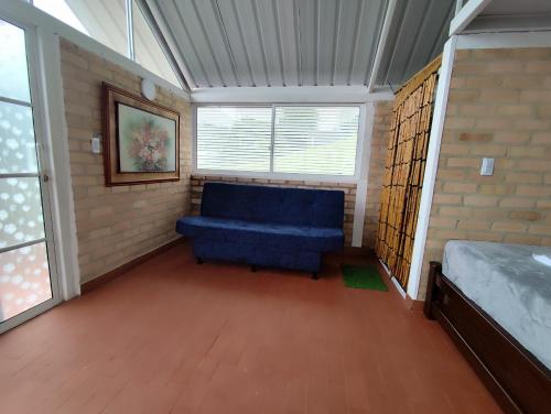 a living room with a blue couch and a window at Cabaña Amanecer Natural Popayán in Popayan