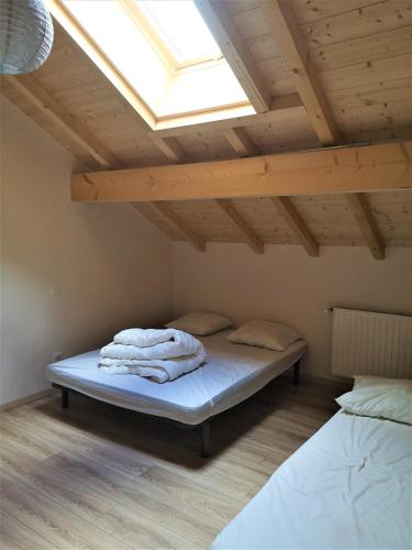 une chambre avec un lit sous un toit avec une lucarne dans l'établissement Grand gîte des Marolais, à Mont-Saxonnex