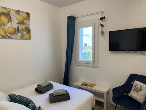 a room with two beds and a tv and a chair at L Abri-côtier Appartements in Saintes-Maries-de-la-Mer