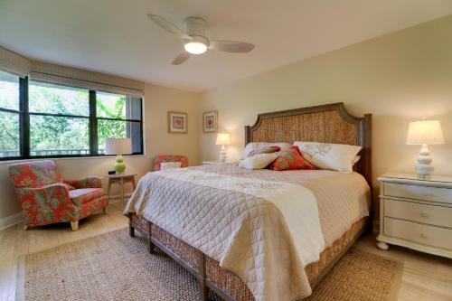 a bedroom with a bed and a chair and windows at Pine Cove 204 in Sanibel