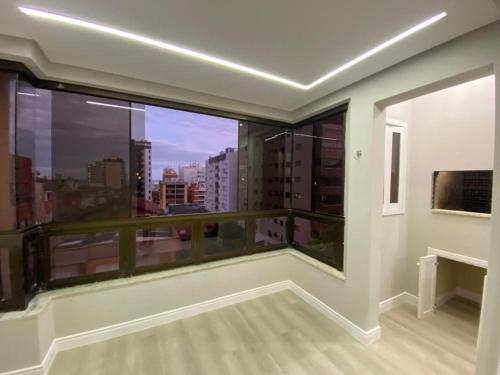 een kamer met een balkon met uitzicht op de stad bij Apartamento família rua Marabá 1495 in Capão da Canoa