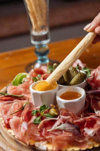 a plate of food with meat andiments on a table at Gaarten Hotel Benessere Spa by Kleos Group Collection in Gallio