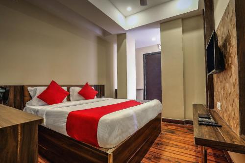 a bedroom with a large bed with red pillows at Capital O SKY GRAND in Hyderabad