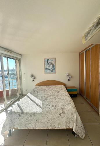 une chambre avec un grand lit et une grande fenêtre dans l'établissement Appartement - Cap d'Agde Vue Port, au Cap d'Agde