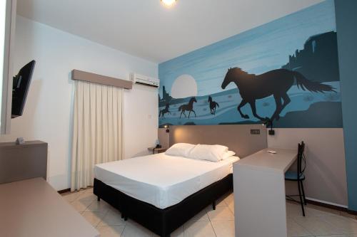 a bedroom with a bed with a painting of a horse on the wall at ibis Styles Presidente Prudente Portal D'Oeste in Presidente Prudente