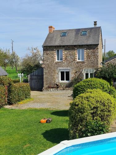une maison en briques avec une piscine en face de celle-ci dans l'établissement Le Jardin B&B, à Isigny-le-Buat