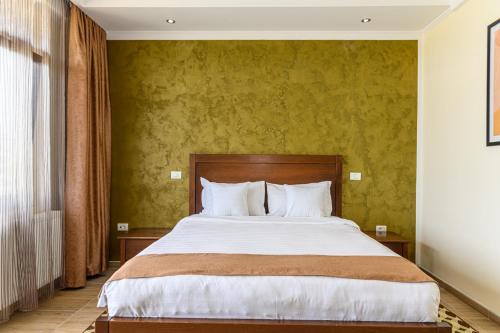 a bedroom with a large bed with green walls at DENY INN Funland in Zărneşti