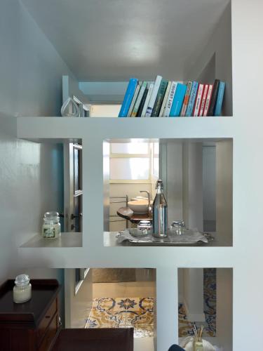 two white shelves filled with books and a table at B&B La Villa in Giardini Naxos