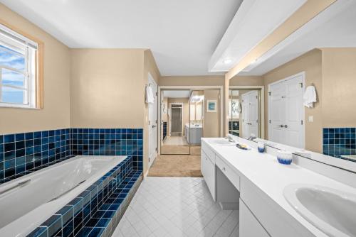 a bathroom with three sinks and a tub at Gone Coastal in Sanibel