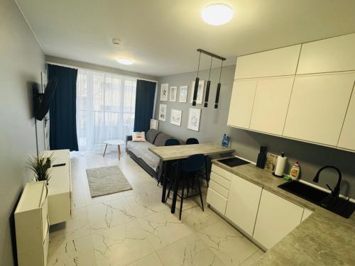 eine Küche und ein Wohnzimmer mit einem Tisch und einer Couch in der Unterkunft Natura Resort Rozewska in Jastrzębia Góra