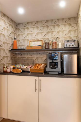 une cuisine avec des placards blancs et un comptoir avec un four micro-ondes dans l'établissement Hôtel Avama Prony, à Paris