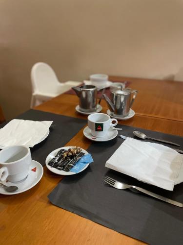 a wooden table with plates and cups and utensils at Miranda Village House in Miranda do Corvo