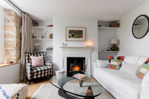 a living room with a white couch and a fireplace at Painter's Cottage in the Cotswolds in Woodchester