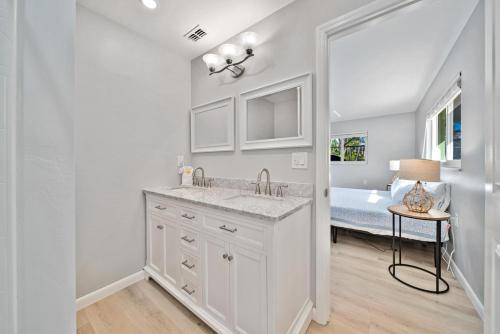 a white bathroom with a sink and a bed at Sunken Treasure in Sanibel