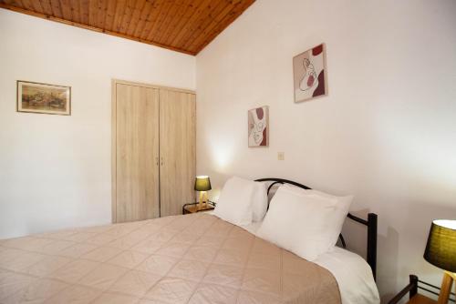 a bedroom with a bed with white walls and a wooden ceiling at Anthoula's garden apartments in Perivolion