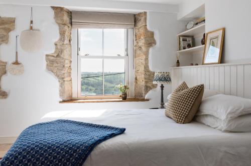 a bedroom with a large bed with a window at Painter's Cottage in the Cotswolds in Woodchester