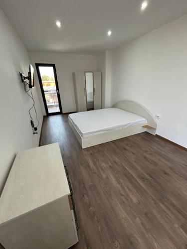 a bedroom with a white bed and wooden floors at Денерис in Dobrich