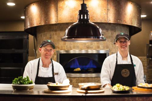 two chefs standing in a kitchen with plates of food at Lodges at Deer Valley in Park City