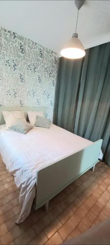 un grand lit dans une chambre avec une lumière dans l'établissement Vos vacances à la mer, à Valras-Plage