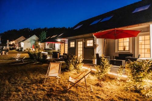 a house with chairs and an umbrella in the yard at Ferienhäuser Insel Usedom Haus Jojo 7 - Blick aufs Achterwasser! Whirlpool und Sauna in Lütow